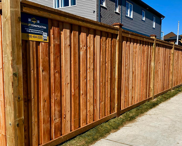 Street view of a residential custom wood board on batten fence.